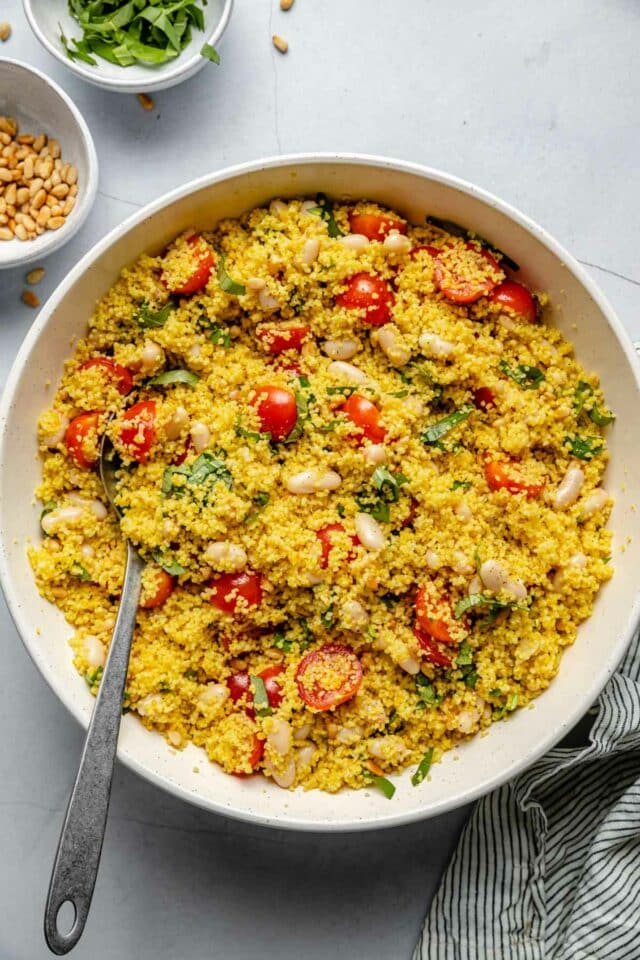 Couscous salad mixed together in a large white serving bowl.