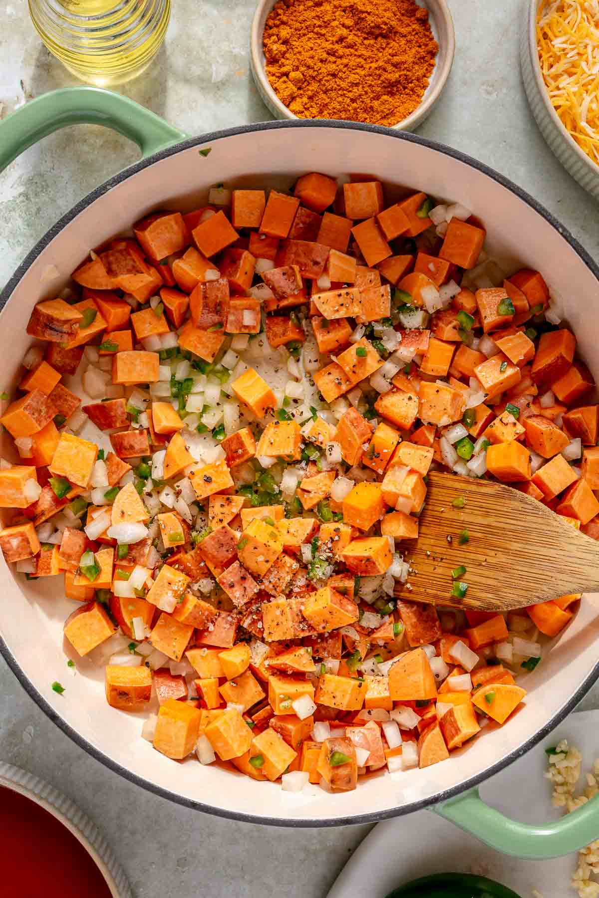 Sautéing diced sweet potato, onion and jalapeños in a pan.