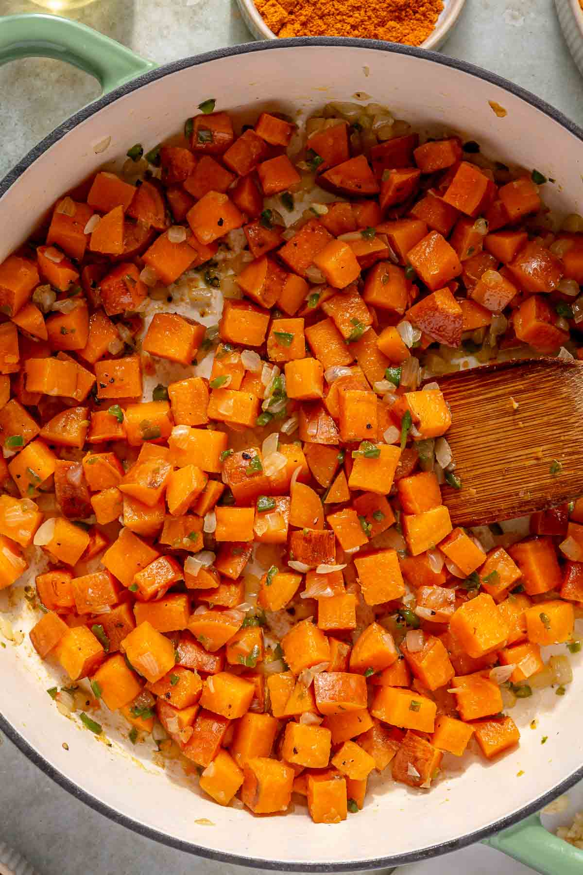 Stirring sweet potato with onion in a pan.
