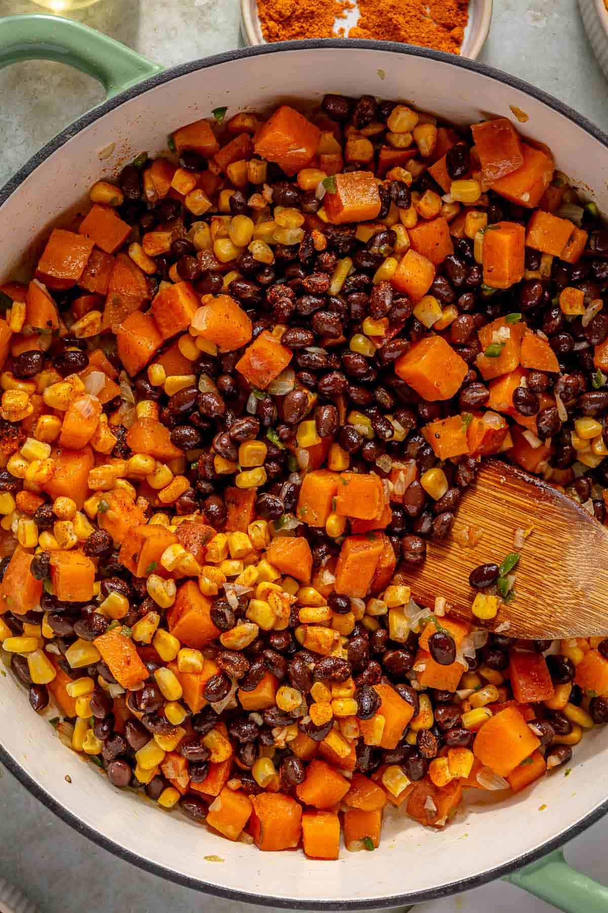 Cooking black beans and corn with sweet potato mixture in a pot.