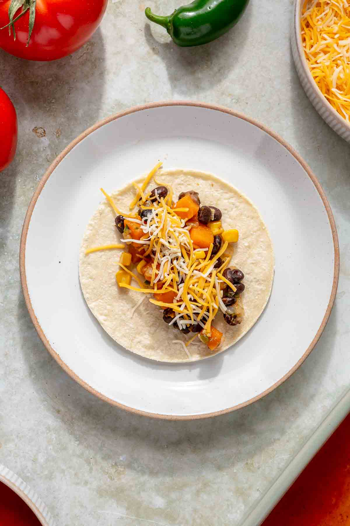 Adding filling and cheese to tortillas.