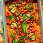 Sweet potato black bean enchiladas topped with avocado slices, green onions and diced tomatoes.