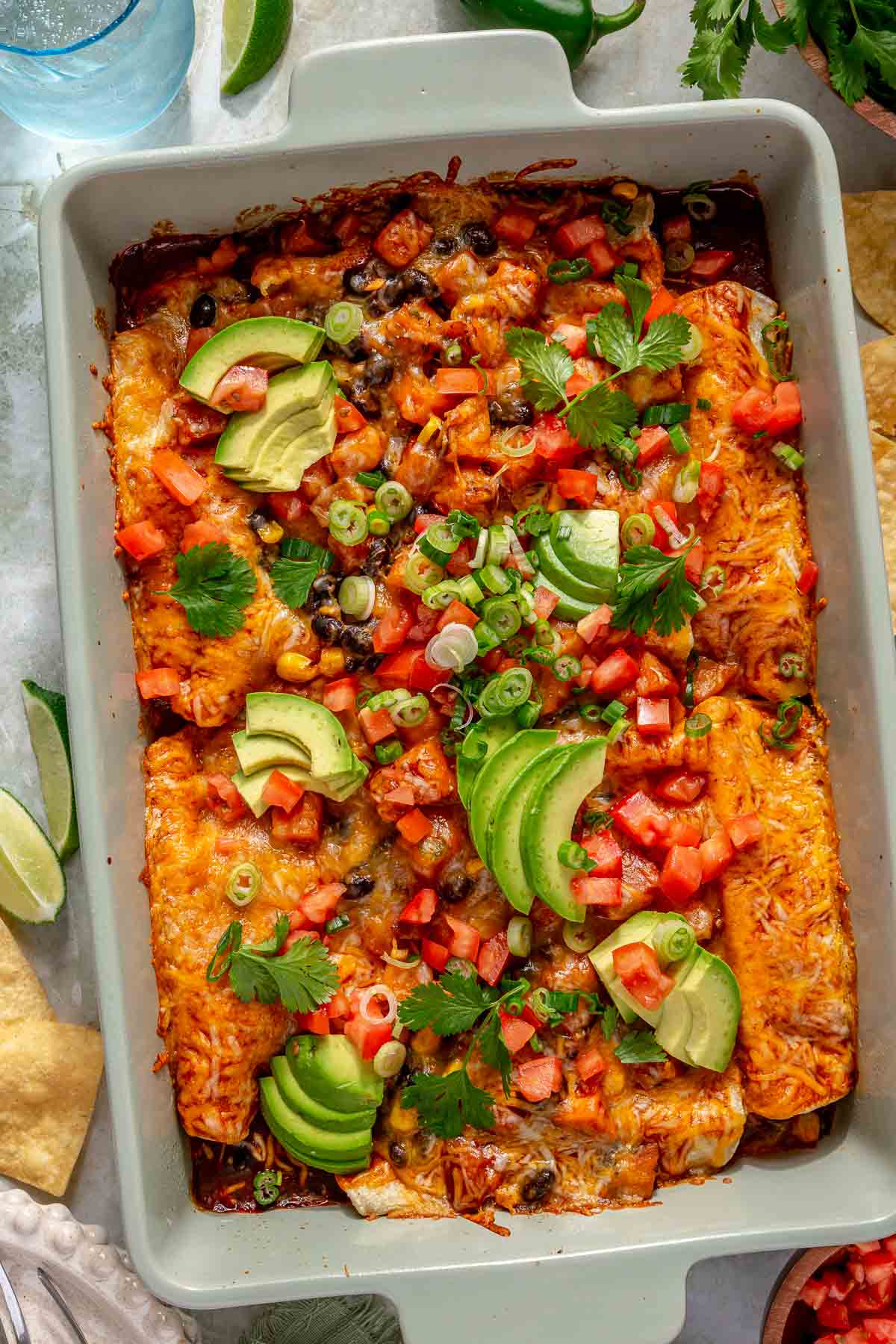 Sweet potato black bean enchiladas topped with avocado slices, green onions and diced tomatoes.