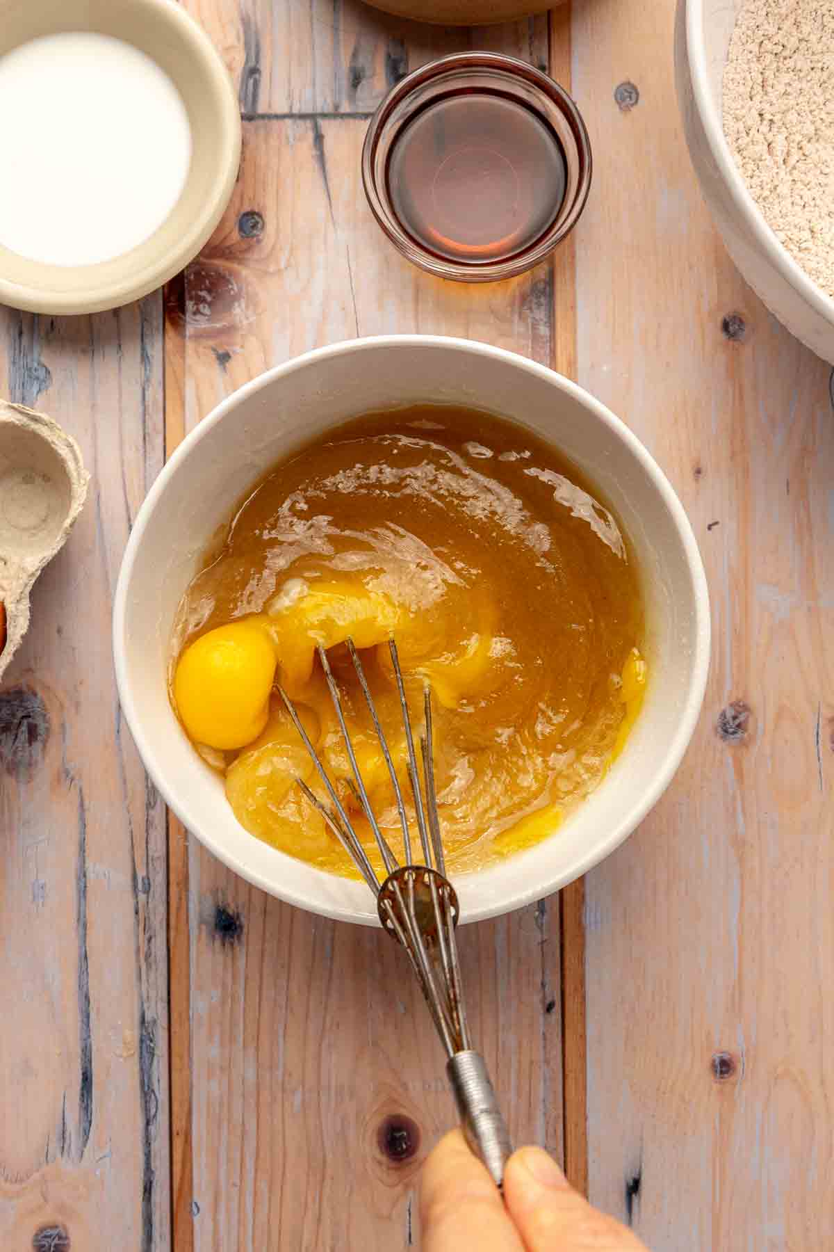 Whisking eggs with vanilla, oil, applesauce and sugar.
