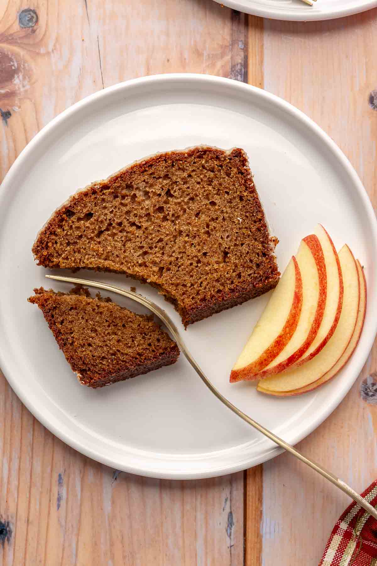 Slice of applesauce bread on a white plate with apple slices.