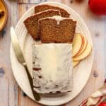 Glazed loaf of applesauce bread on a large white serving plate.