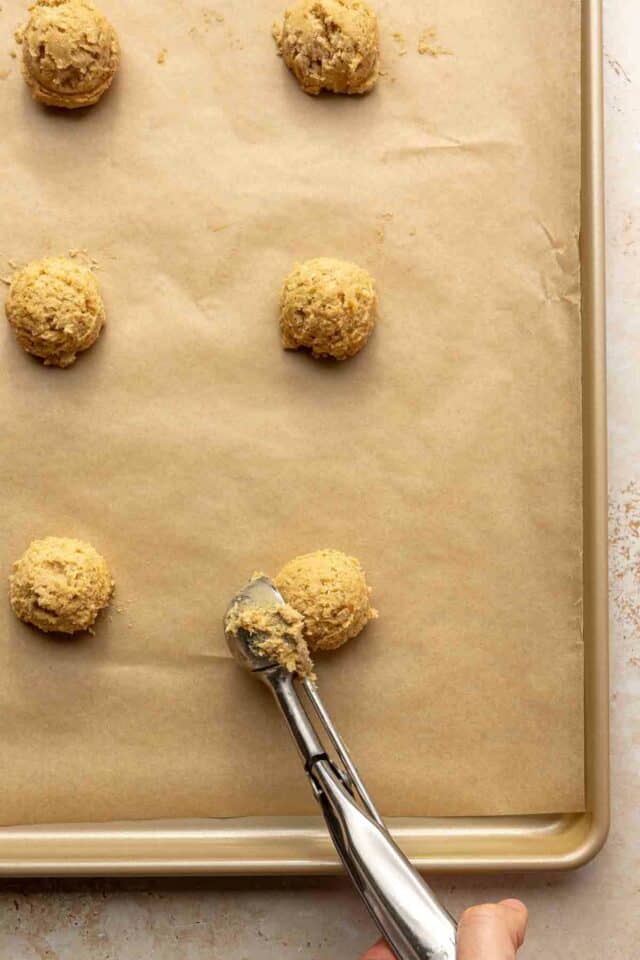 Using a cookie scoop to drop dough balls onto a cookie sheet.