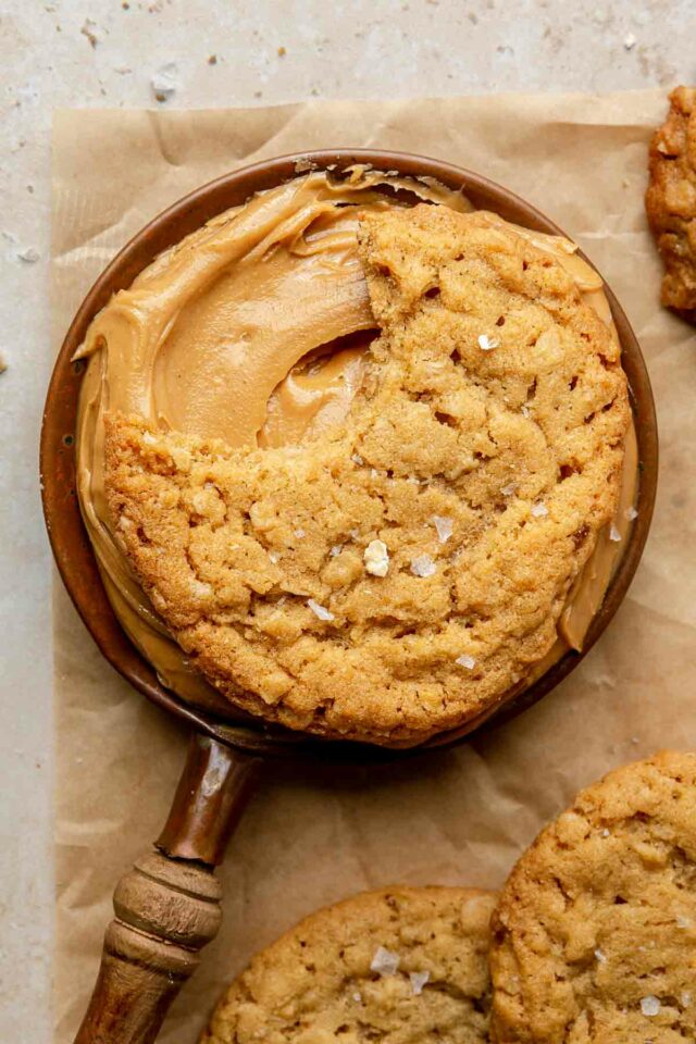 Peanut butter cookie sitting on a cup of peanut butter.