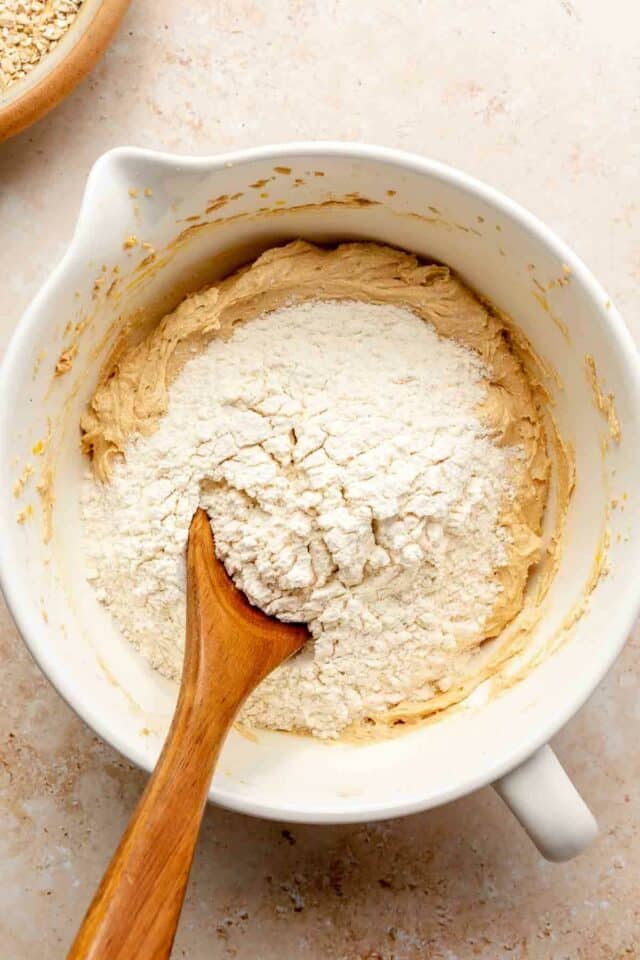 Adding flour mixture to peanut butter mixture in a bowl.