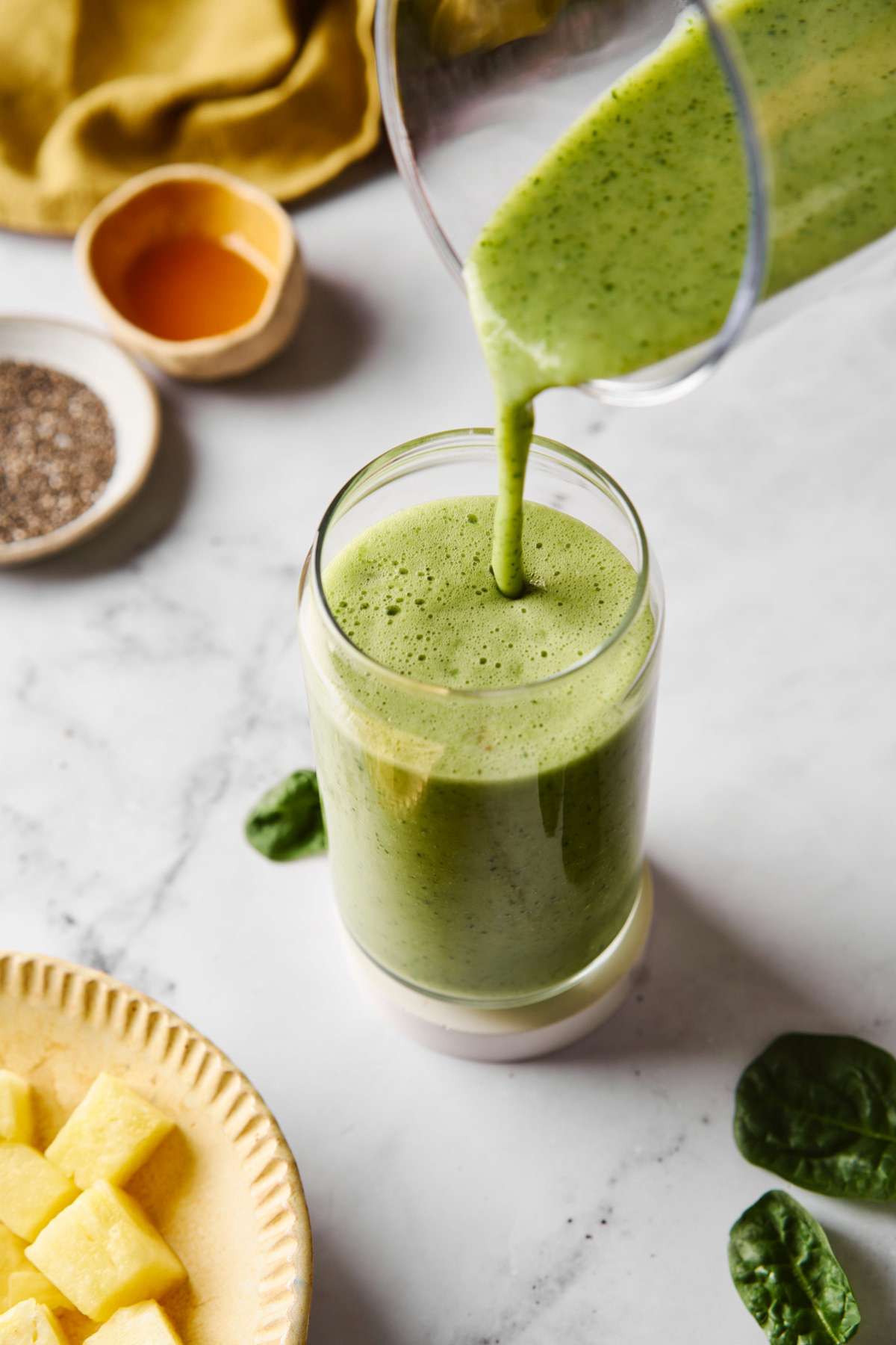 Pouring a green smoothie from a blender into a glass.