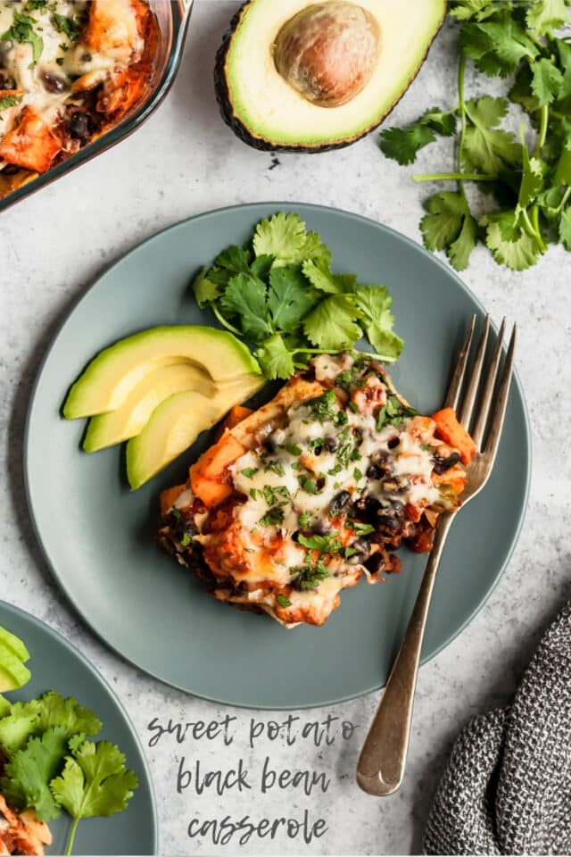 Sweet Potato Black Bean Casserole served on a blue plate with a fork, avocado slices and fresh cilantro