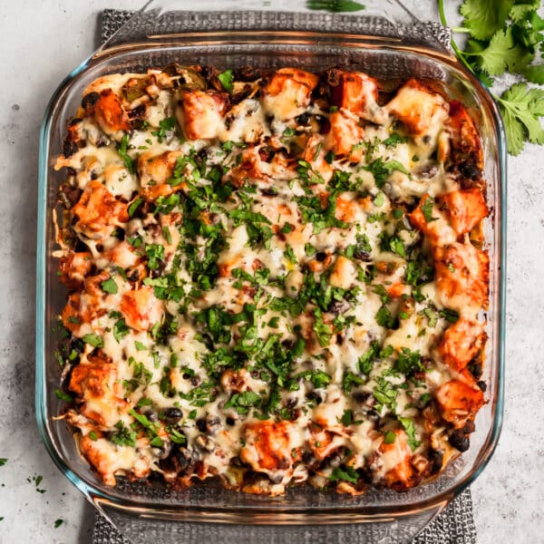 Mexican enchilada casserole topped with chopped fresh cilantro in a square glass baking dish