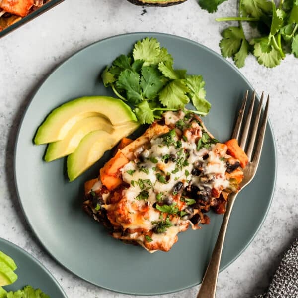 serving of Mexican casserole on a blue plate with avocado slices and cilantro