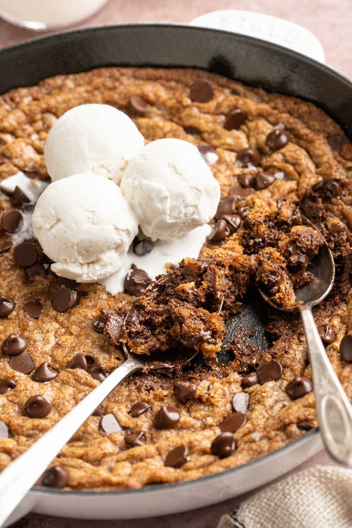Spoons digging into a chocolate chip skillet cookie.