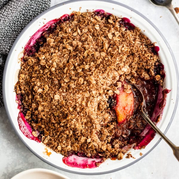 Easy Peach Blueberry Crisp in a white pie plate with a silver serving spoon.