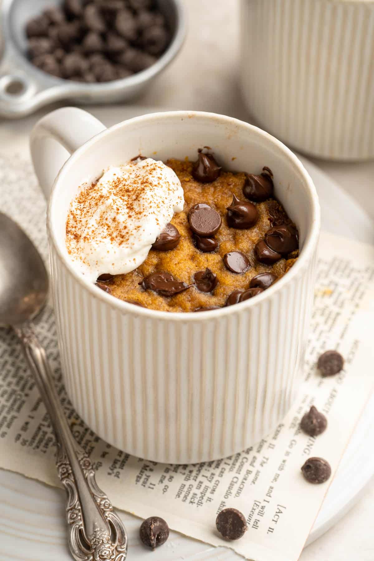 Pumpkin mug cake topped with whipped cream and chocolate chips.