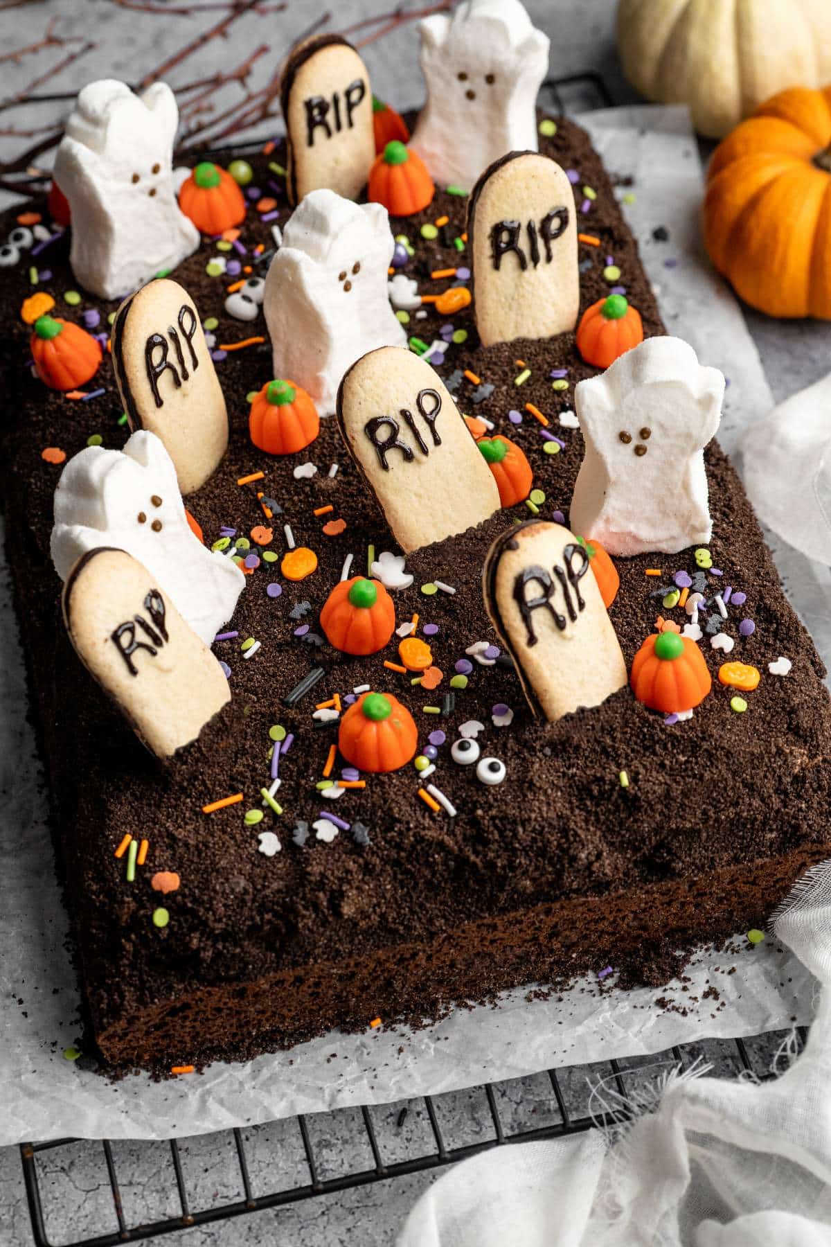 Chocolate cake dessert decorated like a graveyard with ghost Peeps and candy pumpkins.