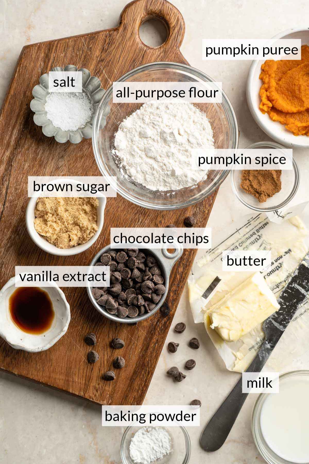 Small bowls of flour, sugar, chocolate chips, vanilla and salt on a cutting board.