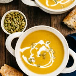 butternut squash soup served in white bowls with crusty bread
