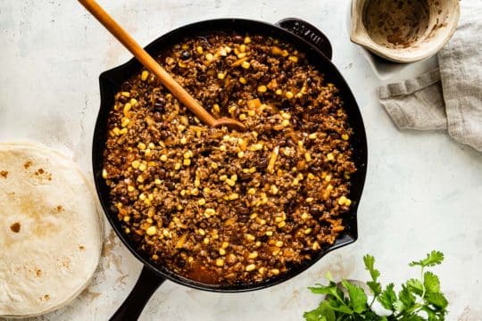 Cooking ground beef with enchilada sauce, black beans and corn.