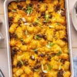 Tater tot casserole in a white casserole dish.