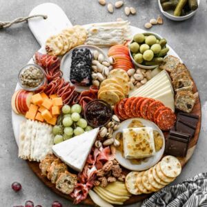 Charcuterie board with meats, cheeses, crackers, chocolate and olives.