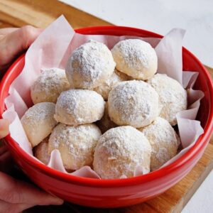 Snowball cookies in a red bowl.