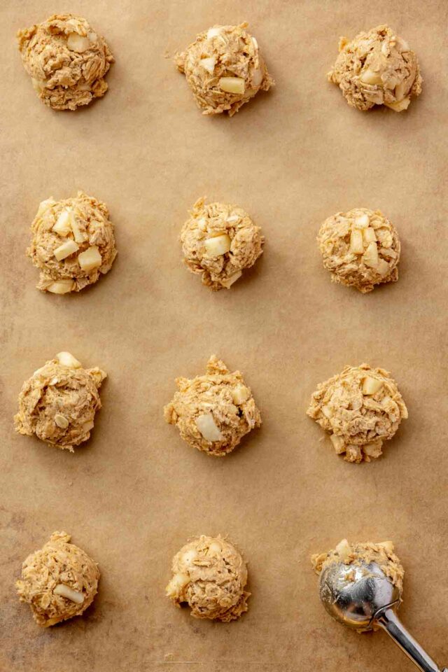 Placing cookie dough balls on a parchment lined cookie sheet.