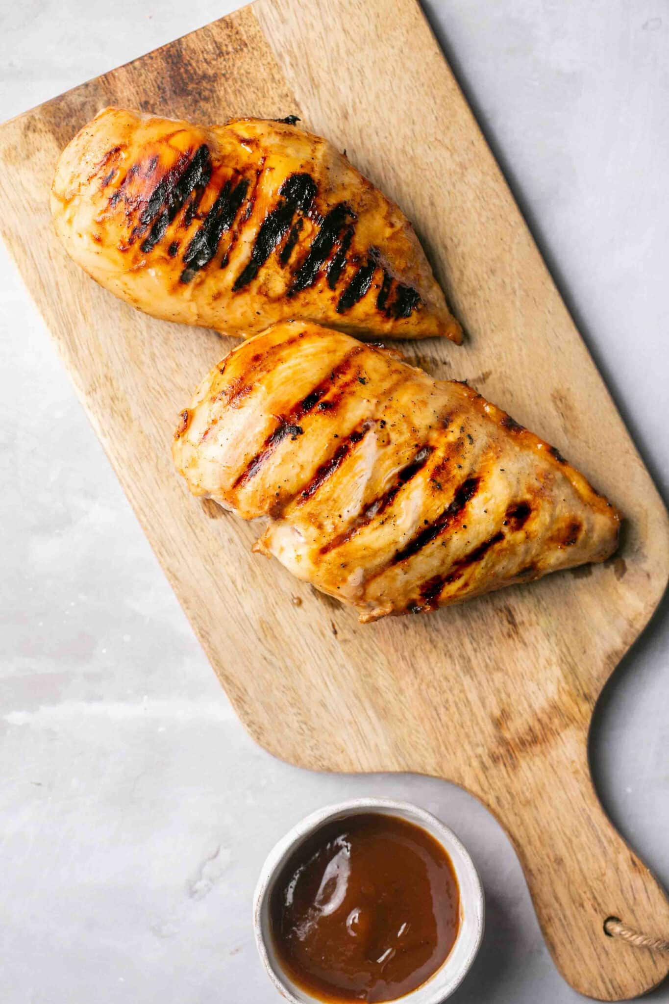 Grilled chicken breasts on a cutting board.