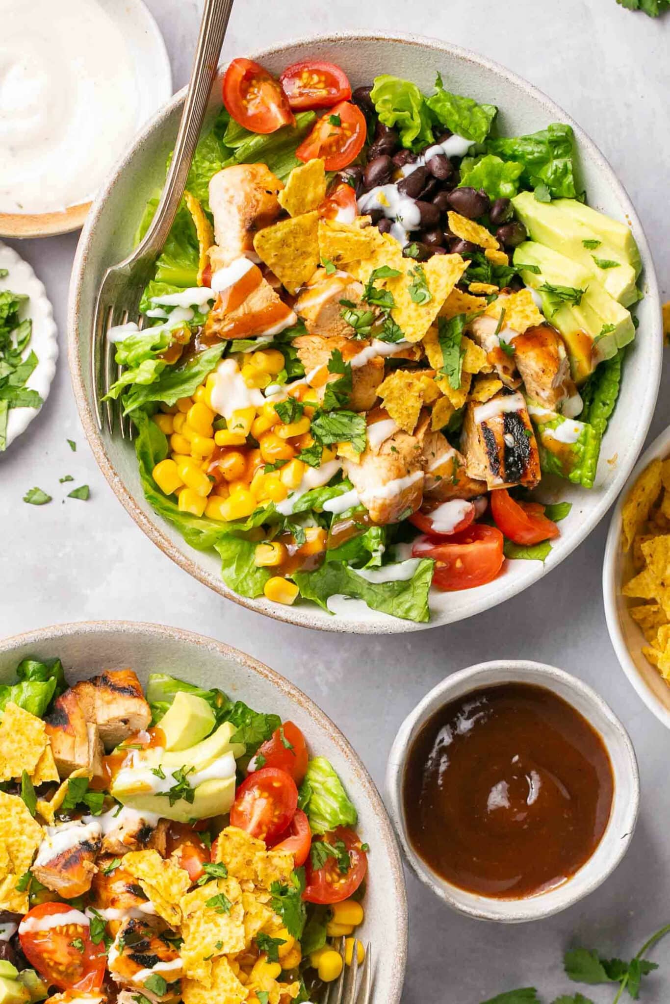 BBQ chicken salad in white bowl near a small bowl of barbecue sauce.