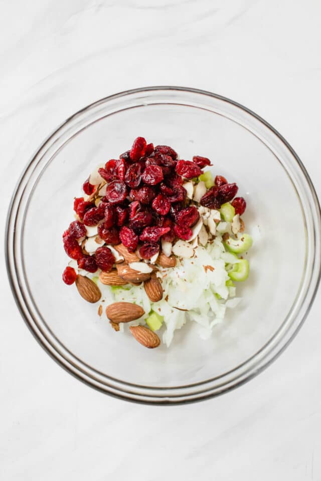 dried cranberries, almonds and celery in a glass bowl 