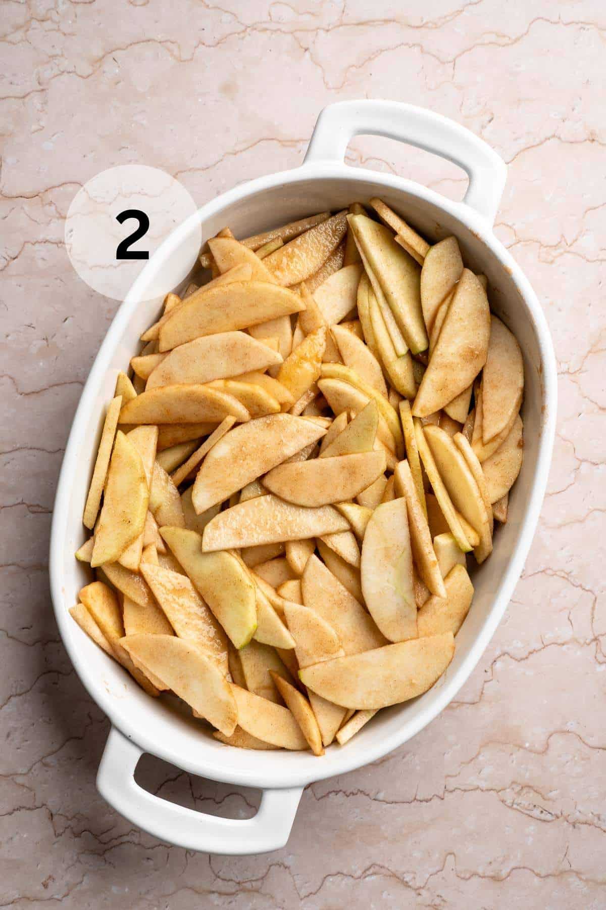 Apple slices in a white baking dish.