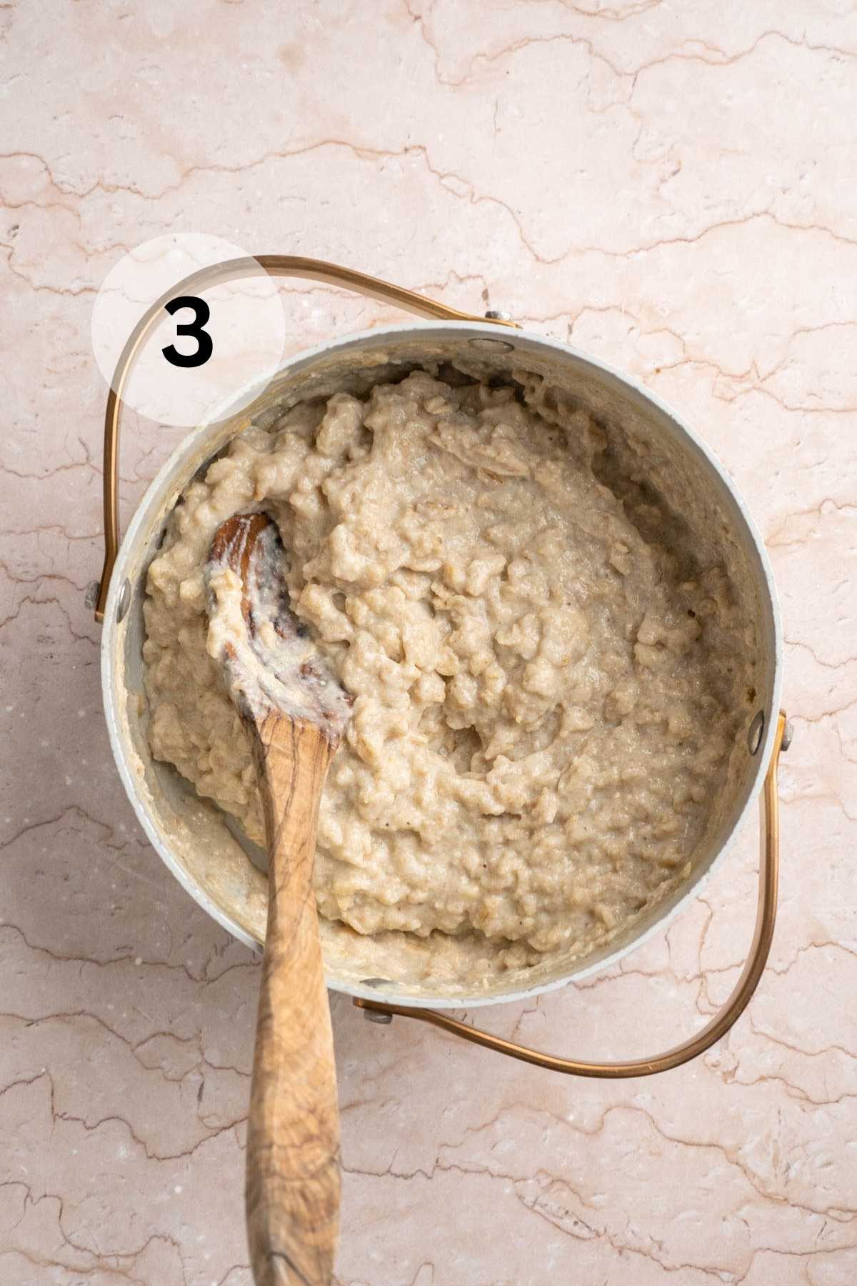 Stirring thick oatmeal in a pot.