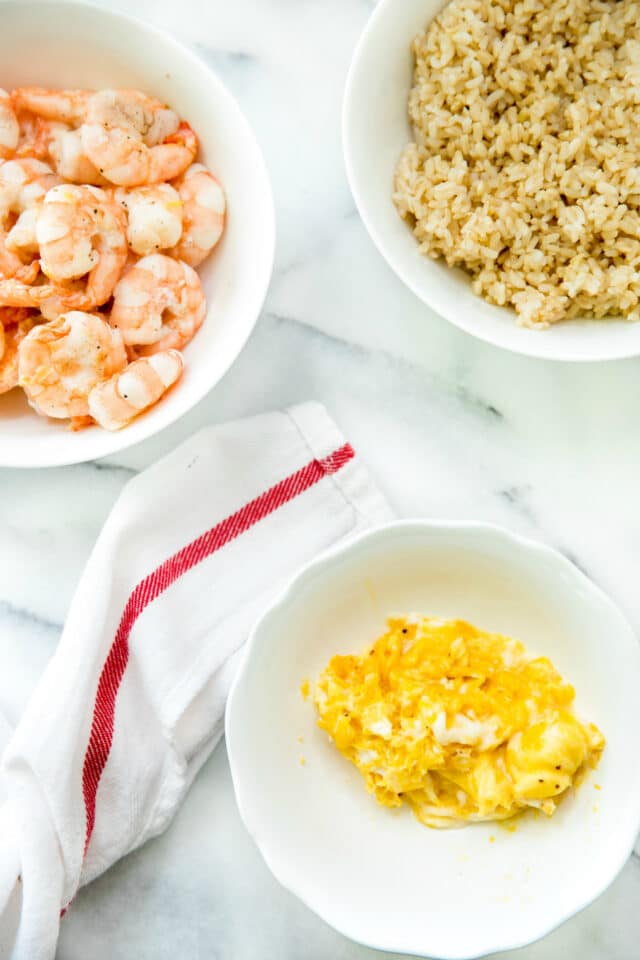 white bowls with scrambled eggs, brown rice and shrimp