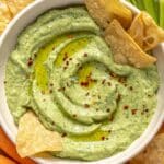 Avocado dip with tortilla chips dipped in it.