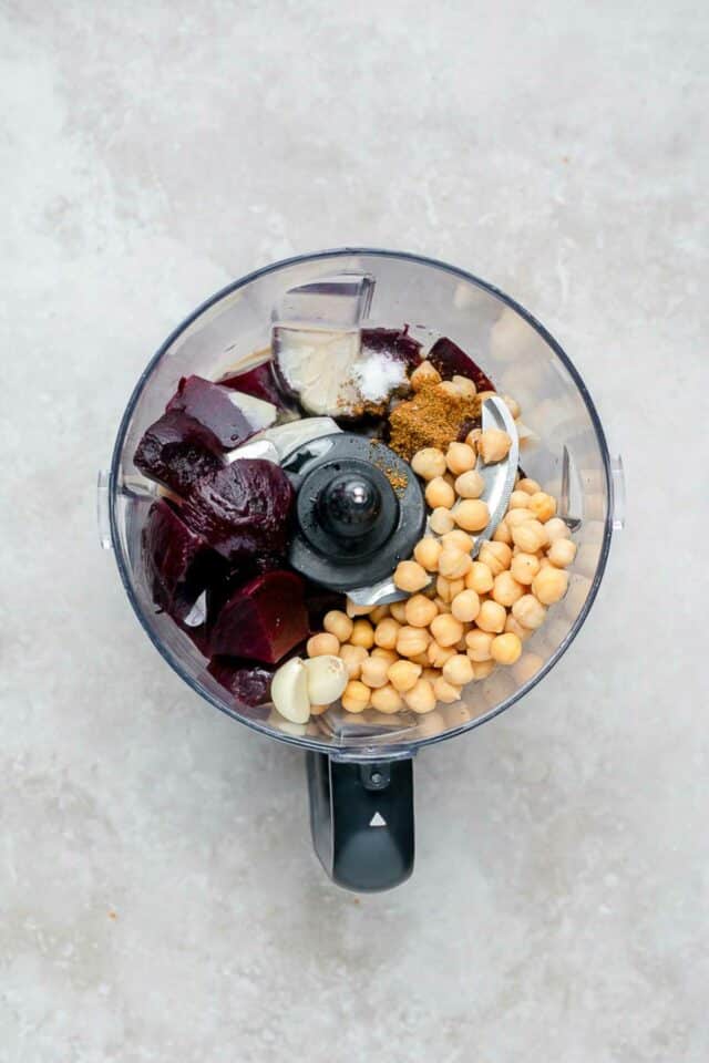 Beets, chickpeas, garlic and seasonings in the bowl of a food processor.