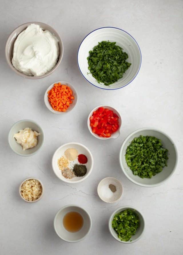 Ingredients for veggie dip divided into small bowls.
