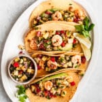 shrimp tacos served on a white platter with a side of pineapple salsa