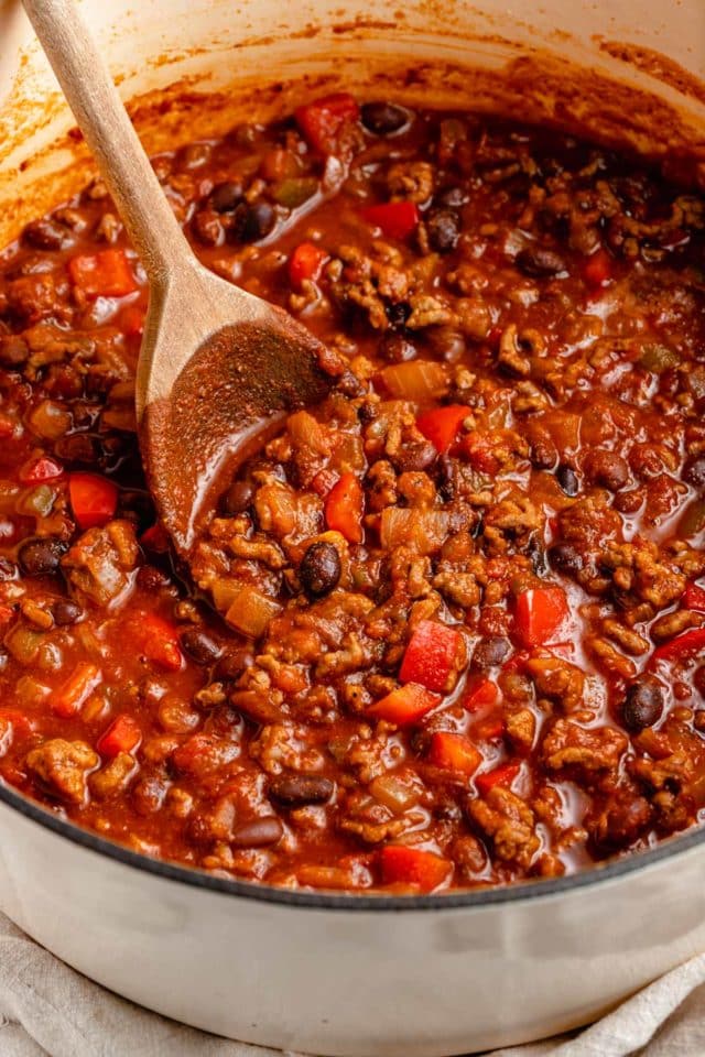 stirring chili with a wooden spoon