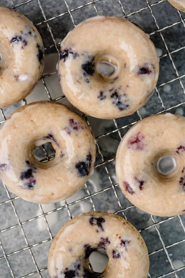baked blueberry donuts topped with glaze on a wire cooling rack