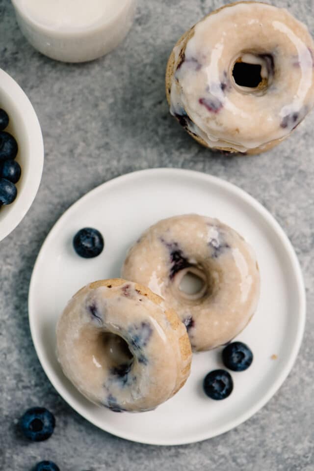 Baked Blueberry Donuts on a white plate served with fresh blueberries