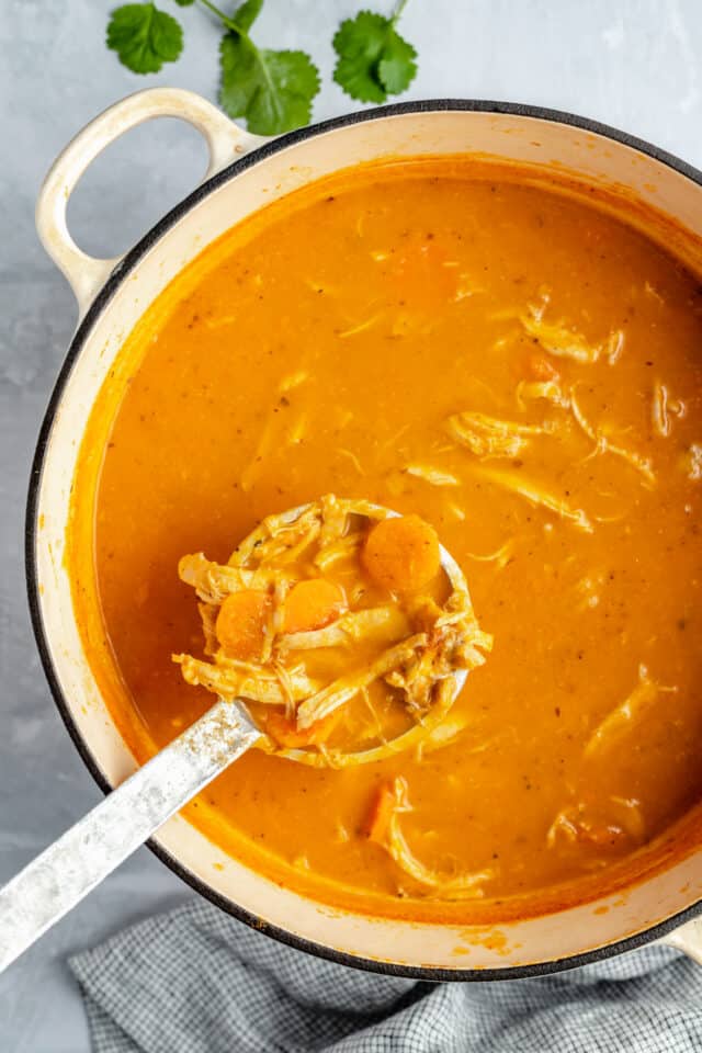 using a ladle to serve soup from pot filled with chicken tortilla soup
