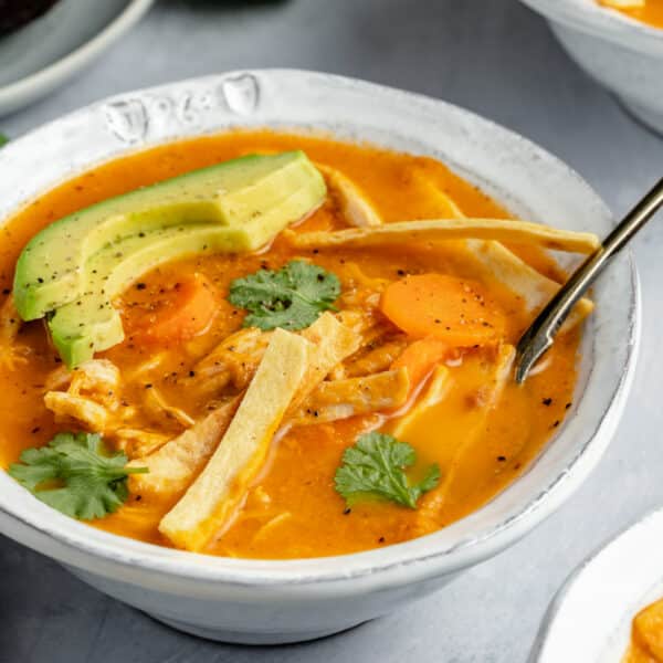 healthy chicken tortilla soup served with tortilla strips and slices of avocado