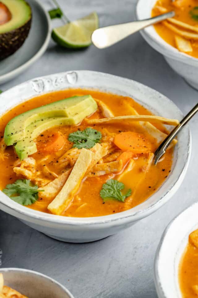 healthy tortilla soup served with tortilla strips and slices of avocado