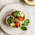 Sweet Potato Black Bean Burritos on a white plate garnished with cilantro.