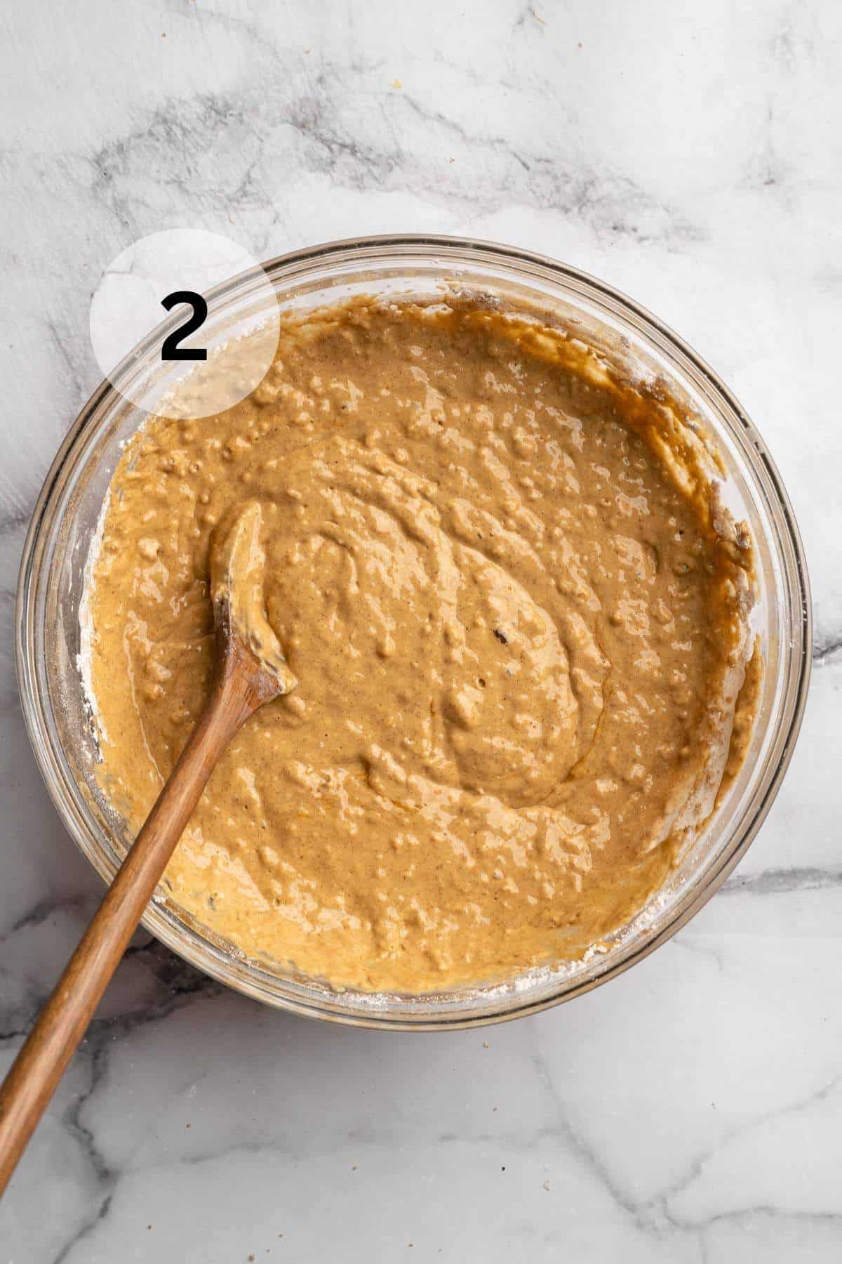 Stirring pancake batter with a large wooden spoon.