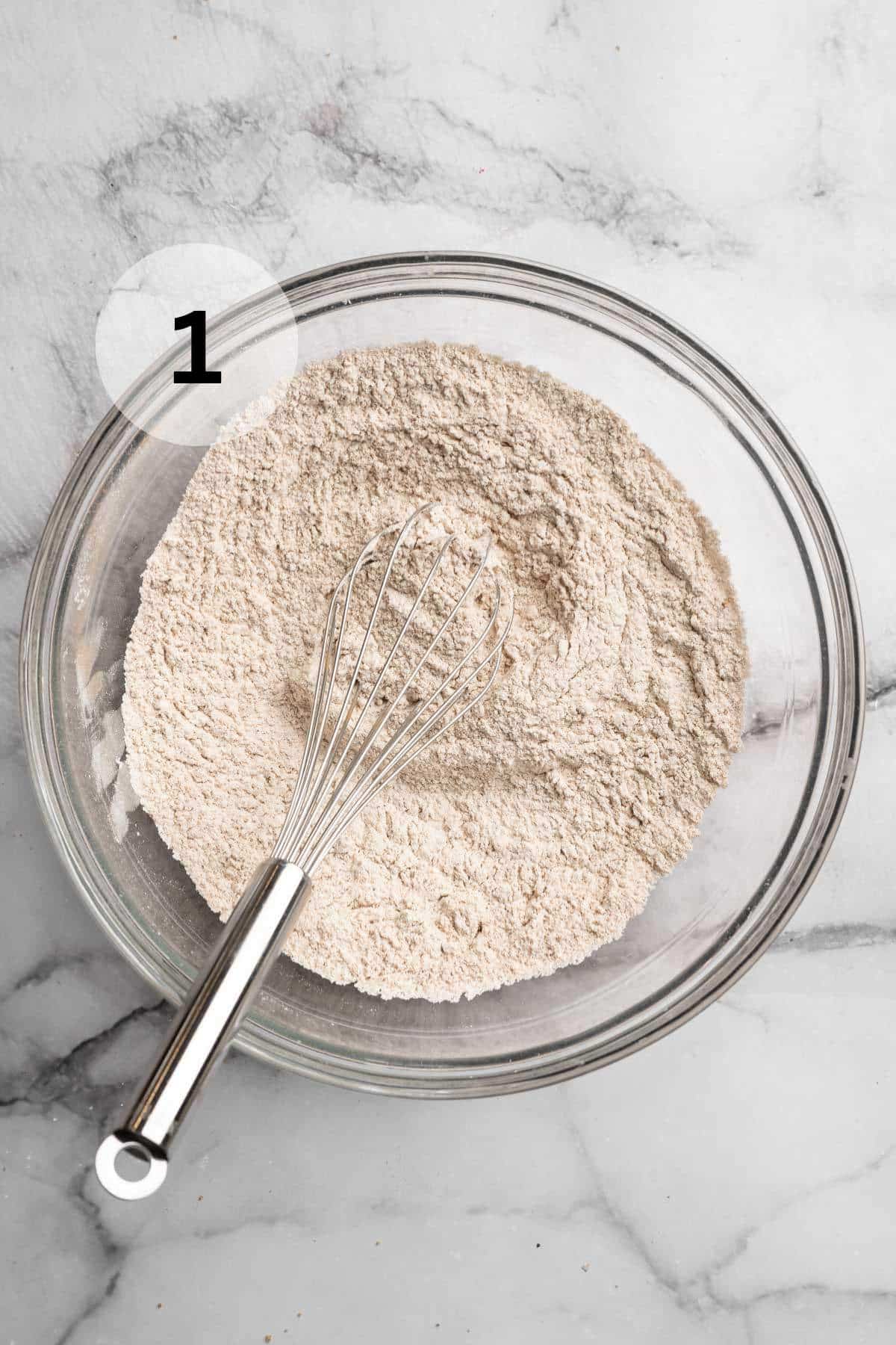 Whisking flour with spices in a large bowl.