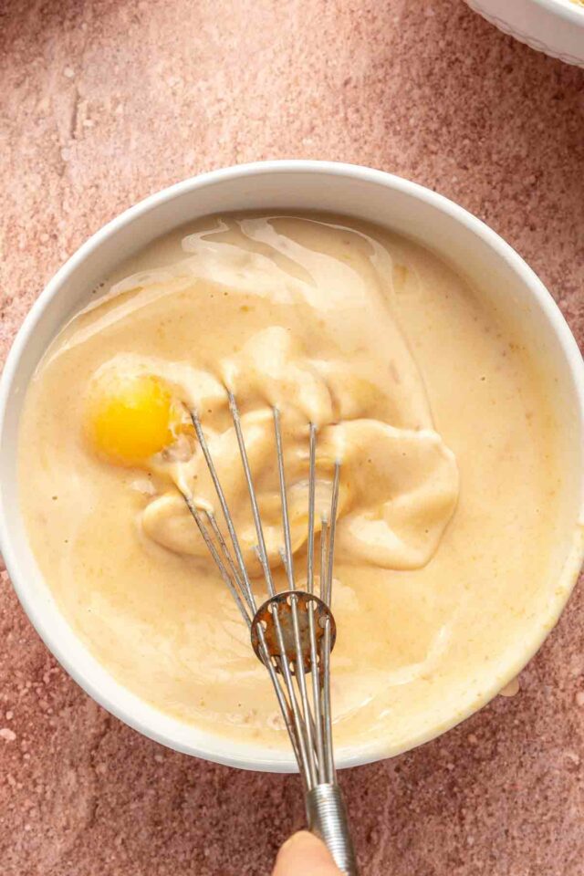 Using a whisk to combine eggs with milk and pumpkin.