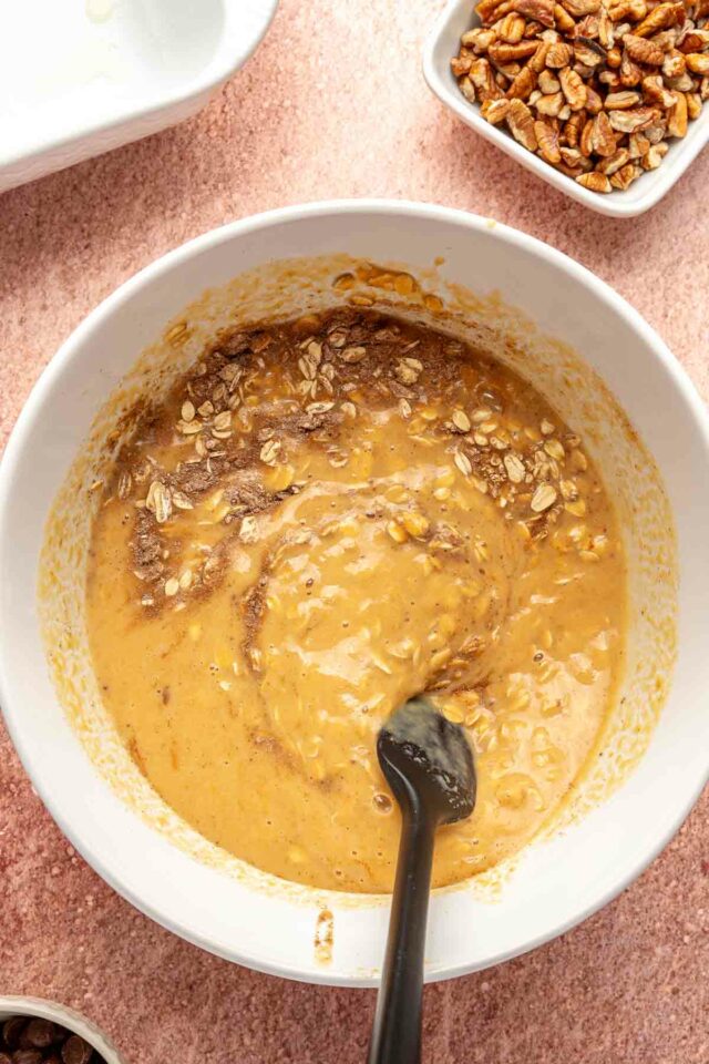 Combining oat mixture with pumpkin mixture in a large bowl.