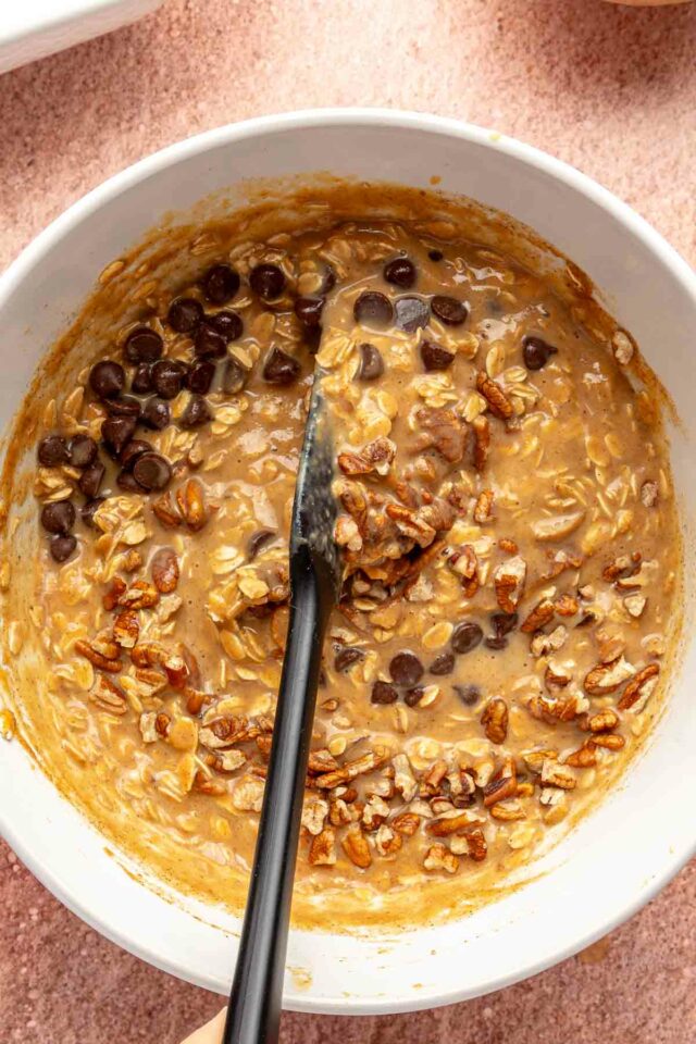 Stirring chopped pecans and chocolate chips into oatmeal mixture.